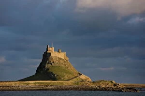 Lindisfarne Castle bathed in afternoon sunlight against a stormy sky, Holy Island