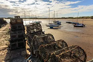 Fishing Prints: Lobster pots on harbour wall and yachts on beach at low tide on a summer evening