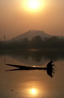 Silhouettes Prints: A local fisherman peers into the calm waters of Nigeen Lake on a winter evening in Srinagar