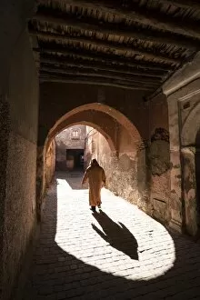 Moroccan Culture Gallery: Local man dressed in traditional djellaba walking through archway in a street in the Kasbah