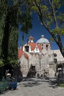 Cupola Prints: Local man resting on a park bench with Iglesia del Carmen in background