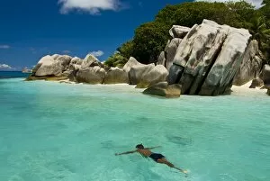 Local man swimming at the Granite rocks at Ile aux Cocos, Seychelles, Indian Ocean