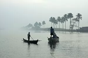 Local villagers paddle shell dredging canoes at sunrise on the backwaters