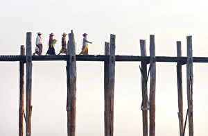 Wooden Post Gallery: Local women walking across U Bein Bridge behind, the worlds longest teak foot bridge spanning 1300