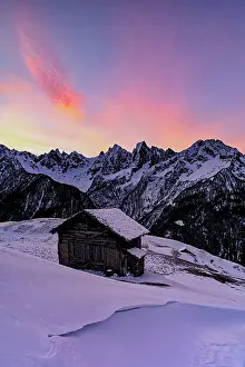 Val Bregaglia Prints: Lone mountain hut in deep snow with majestic peaks in the background at dawn