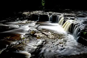 Mossy Prints: Long exposure of a serene waterfall cascading over rocky ledges