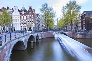 Keizersgracht Prints: Long exposure of a tourist boat crossing canals Keizersgracht from Leidsegracht at dusk