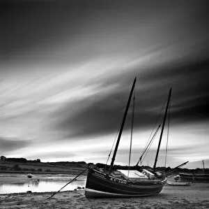 Long exposure used to record moving clouds above old wooden ketch on Aln Estuary at low tide
