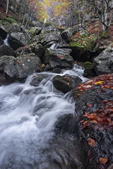 Long exposure of a waterfall flowing between rocks in a wood during autumn, Emilia Romagna, Italy, Europe Long exposure of a waterfall flowing between rocks in a wood during autumn, Emilia Romagna, Italy, Europe