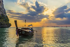 Thai Culture Prints: A long tail boat at sunset on Railay beach in Railay, Ao Nang, Krabi Province, Thailand