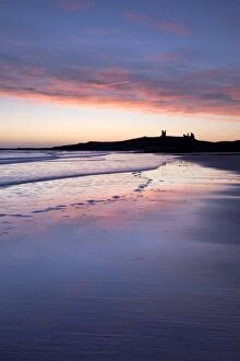Embleton Bay Collection: Looking across Embleton Bay at sunrise towards the silhouetted ruins of Dunstanburgh Castle in