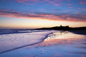 Ruined Gallery: Looking across Embleton Bay at sunrise towards the silhouetted ruins of Dunstanburgh Castle in