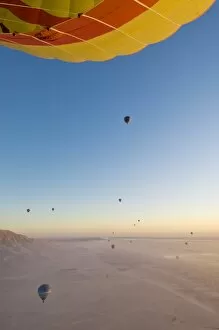 Lots of hot air balloons flying over the desert at sunrise west of the river Nile near Luxor