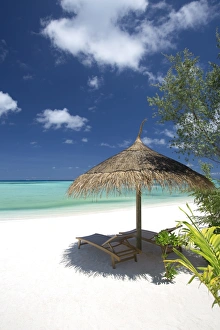 Lounge chairs under shade of umbrella on tropical beach, Maldives, Indian Ocean, Asia