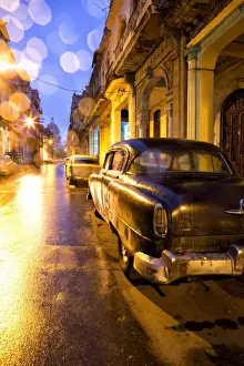 Traditionally Cuban Prints: Low light view along a street towards The Capitolio with street lights reflecting in the wet tarmac