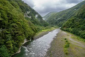 Stones Prints: Lupshara river flows through a green valley in Ritsa Relict National Park with rocky banks and forested hills in Russia