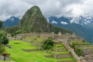 Sights Prints: Machu Picchu shows ancient ruins and green landscape with mountain backdrop in Peru during cloudy weather