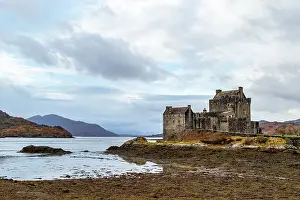 Story Prints: Majestic ancient castle by a serene lake with cloudy skies and mountainous backdrop