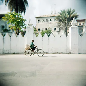 Tanzania Prints: Man on bicycle with old buildings behind, Stone Town, Zanzibar, Tanzania