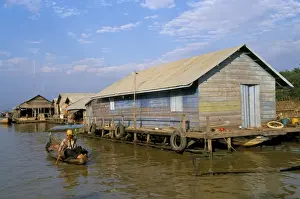 Single Storey Prints: Man in canoe passing a house, floating fishing village of Chong Kneas, Tonle Sap lake