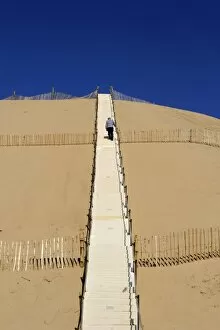 Man climbing steps leading up to Dunes du Pyla, Bay of Arcachon, Cote d Argent