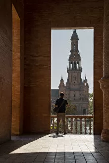 35 39 Years Gallery: Man enjoying the view of Plaza de Espana, framed through an archway, Seville, Andalusia, Spain