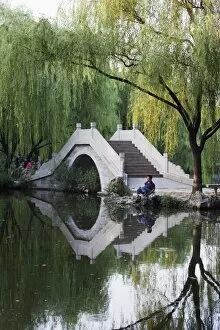 Images Dated 12th September 2008: Man fishing next to a stone arched bridge in Zizhuyuan Black Bamboo Park
