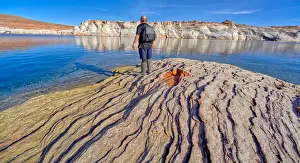 55 59 Prints: Man hiking along rocky shoreline of Lake Powell in an area called the Chains in the Glen