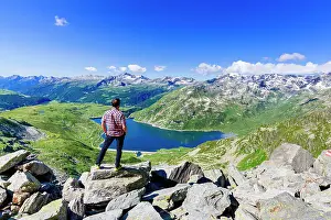 Mid Adults Prints: One man looking at the alpine lake of Montespluga standing on rocks