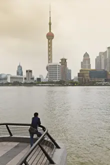 Pu Dong Prints: A man looking at the Oriental Pearl Tower and Pudong skyline across the Huangpu River from the Bund