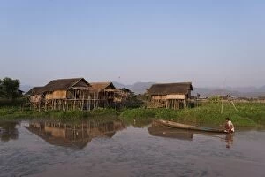 Images Dated 4th April 2010: A man paddles his canoe past one of the floating villages on Inle Lake, Myanmar (Burma)