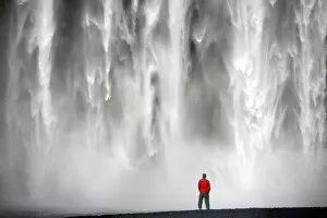 Images Dated 10th May 2010: Man in red jacket standing in front of the 62m high Skogafoss waterfall near the village of Skogar