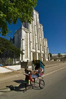 Man with a rickshaw in front of a modern church in Mahajanga, Madagascar, Africa