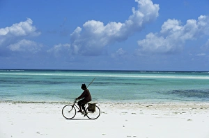 Tanzania Prints: A man riding his bicycle of Kiwengwa beach, island of Zanzibar, Tanzania