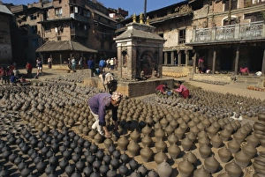 Bhaktapur Prints: Man with rows of clay pots drying in Potters Square