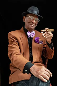 Black Background Prints: Man seated dressed as 1950s dandy or gangster with fedora hat and big cigar