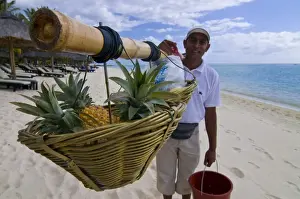 Beachcomber Le Paradis Prints: Man selling pineapples on the beach of the Beachcomber Le Paradis five star hotel