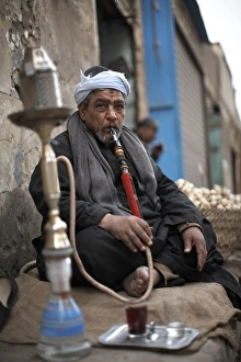 60 65 Years Prints: A man smokes sheesha in the Khan al-Khalili area of Cairo, Egypt, North Africa, Africa