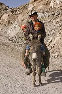 Man with twins on donkey in the mountains near Sary Tash, Kyrgyzstan, Central Asia, Asia