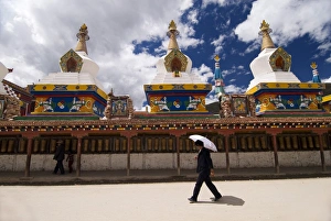 Man with umbrella at temple, Yushu, Qinghai, China, Asia