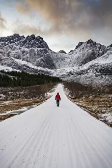 Nordland County Gallery: Man walking on empty mountain road covered with snow in winter, Nusfjord, Nordland county