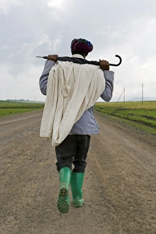 Loneliness Prints: Man walking along the road during the rainy season wearing green boots