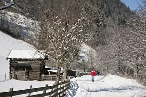 Man walking on Winterwanderweg cleared trail along Alpine valley with snow in winter