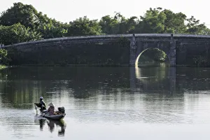 A man and woman fishing from a small boat in the moat around the Citadel in Hue, Vietnam