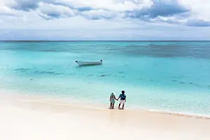 Mid Adults Prints: Man and woman holding hands on a tropical beach admiring the crystal clear sea