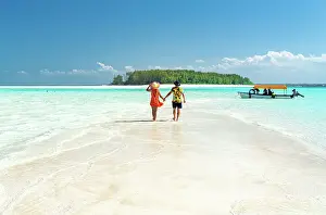 Adults Prints: Man and woman in love holding hands walking on empty sandy shore surrounded by the Indian Ocean