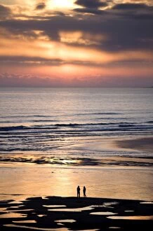 Man and woman in silhouette looking out over North Sea at sunsrise from Alnmouth Beach