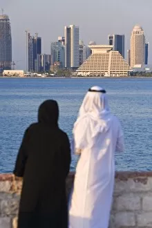 Man and woman in traditional dress looking across Doha