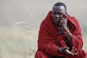Savannah Prints: A Masai man talking on a mobile phone in the African savanna, Masai Mara Game Reserve