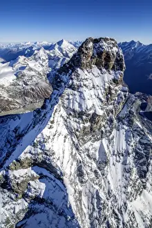 Massif Prints: The massive shape of the Matterhorn sorrounded by its mountain range covered in snow